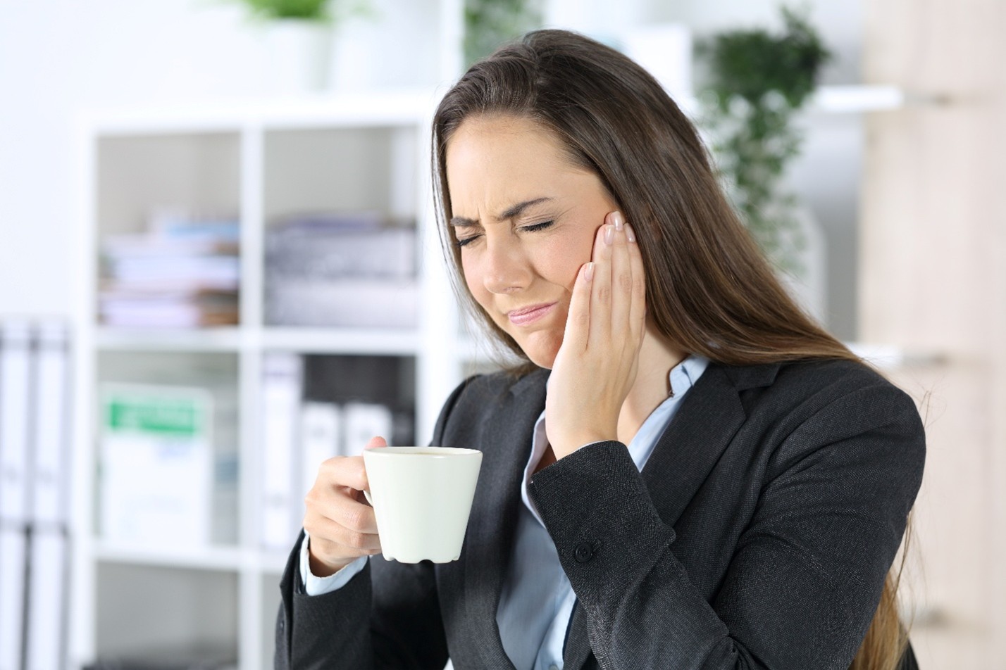 photo of lady holding coffee cup and hand on left jaw